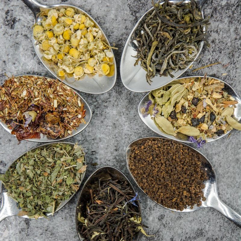 seven different spices and herbs on gray stainless steel spoons