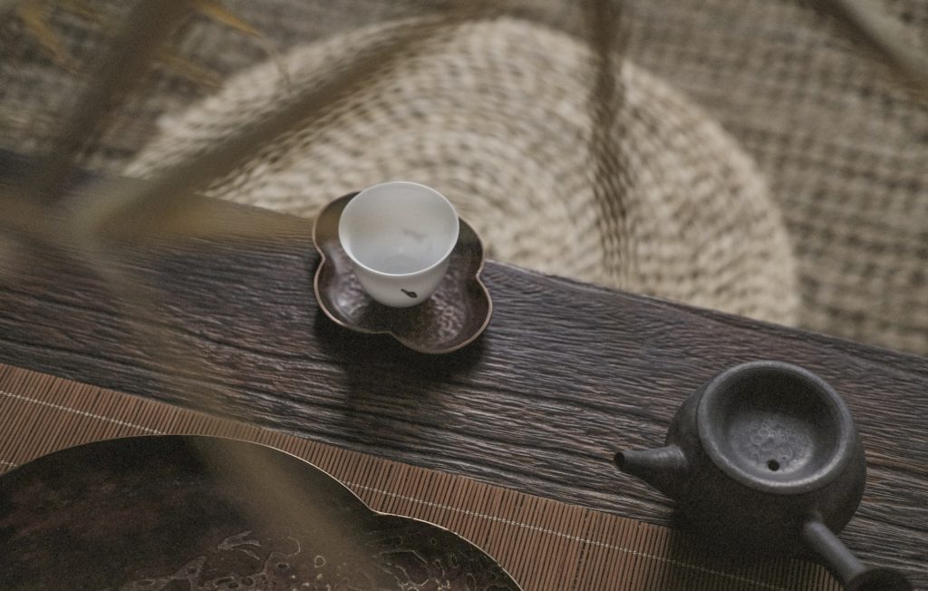 white teacup on saucer near teapot